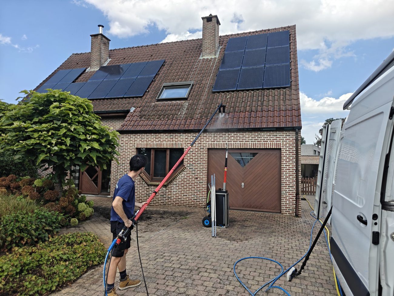 Een medewerker reinigt het dak van een woning met zonnepanelen