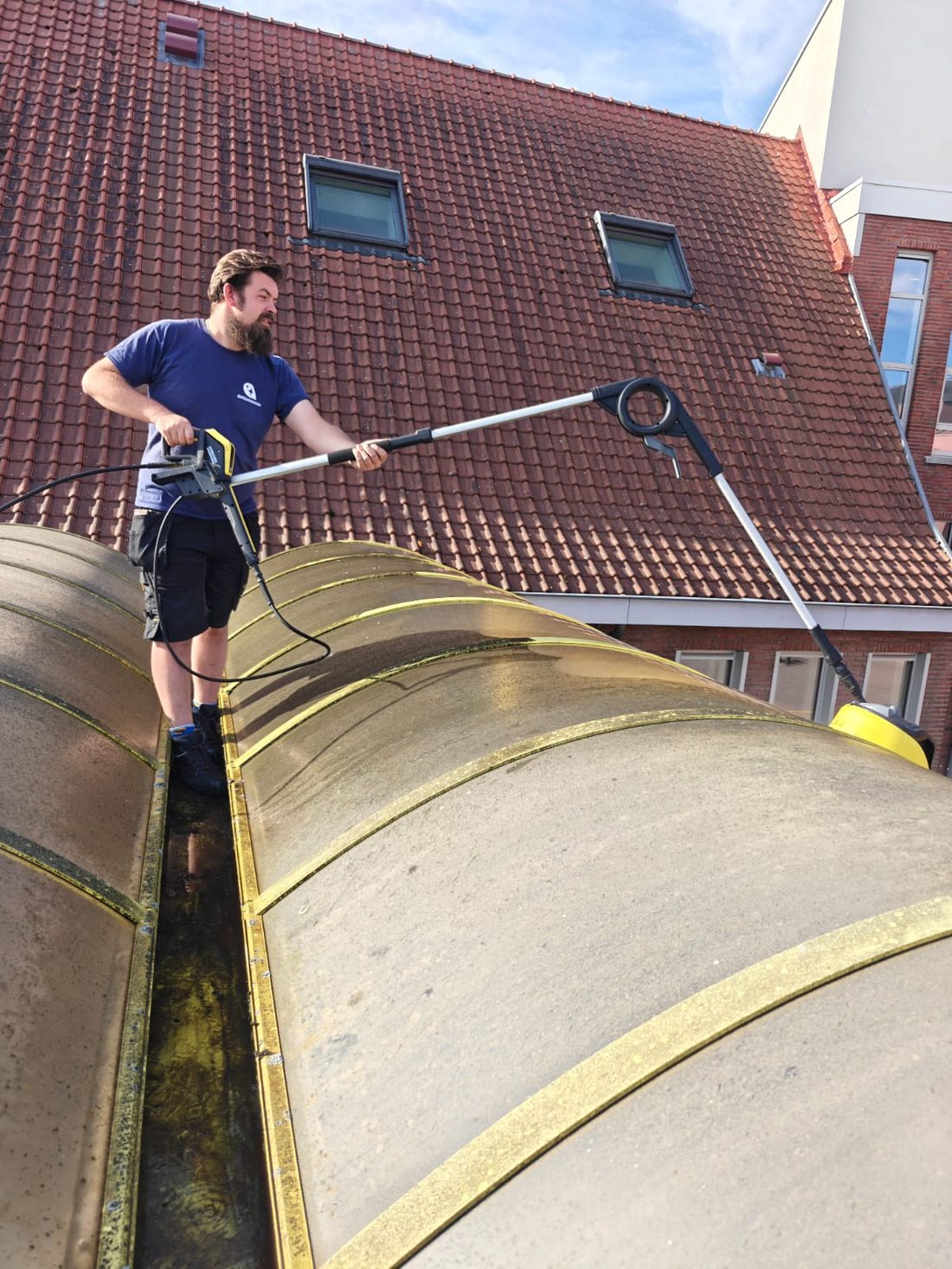 Een medewerker van De Ramenwassers reinigt een verandadak met een hogedrukreiniger